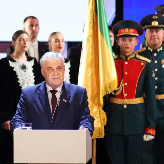 Мужчина в синем костюме выступает с трибуны на торжественной церемонии.
