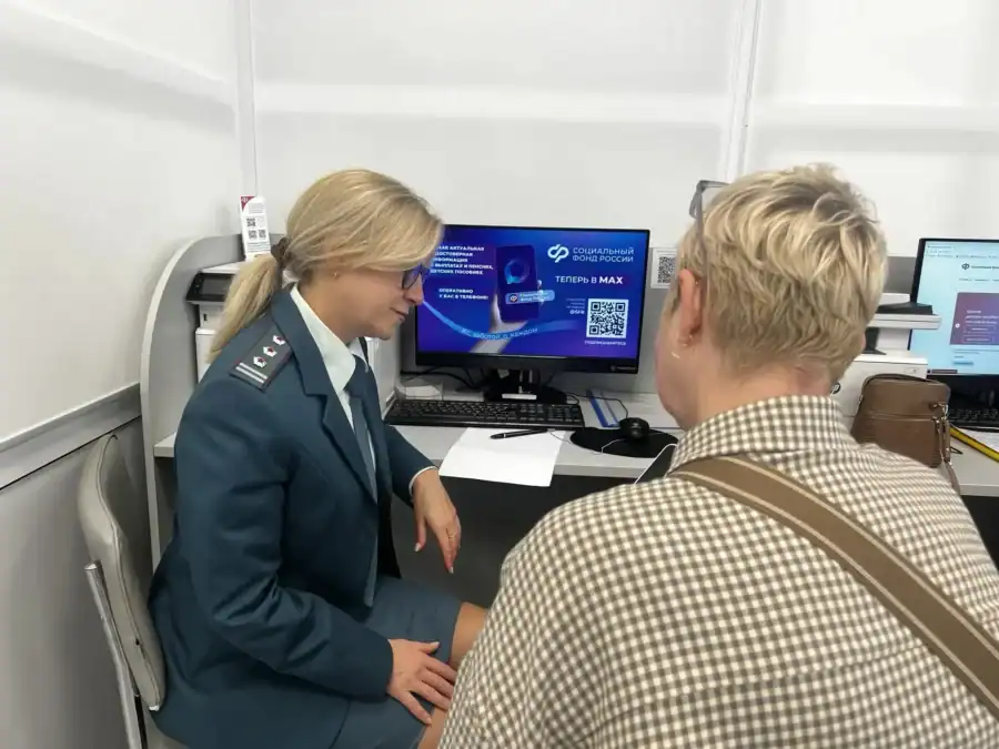 Сотрудница в форменном кителе беседует с посетительницей у компьютерного стола.