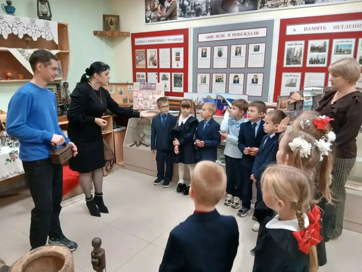 Первоклассники слушают рассказ взрослых у стендов школьного музея.