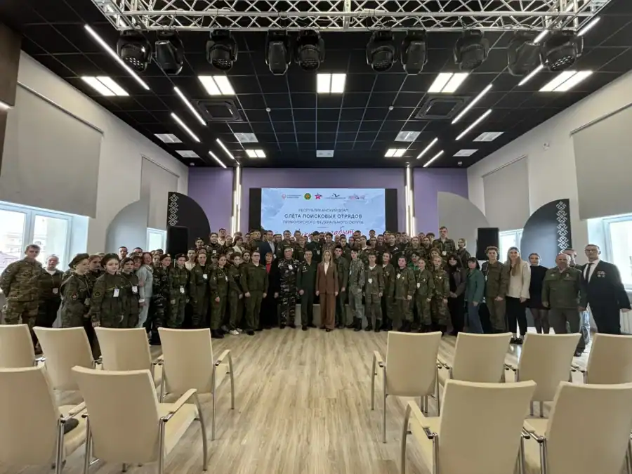 Участники слёта в камуфляжной форме позируют в конференц-зале.