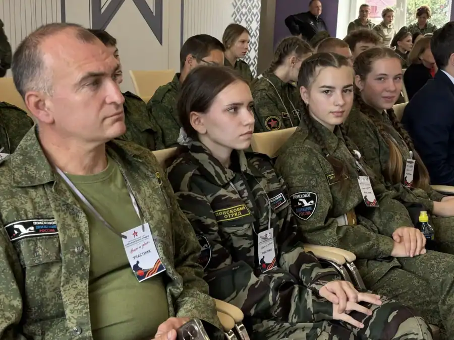 Участники поискового движения в форме сидят на местах в зале.