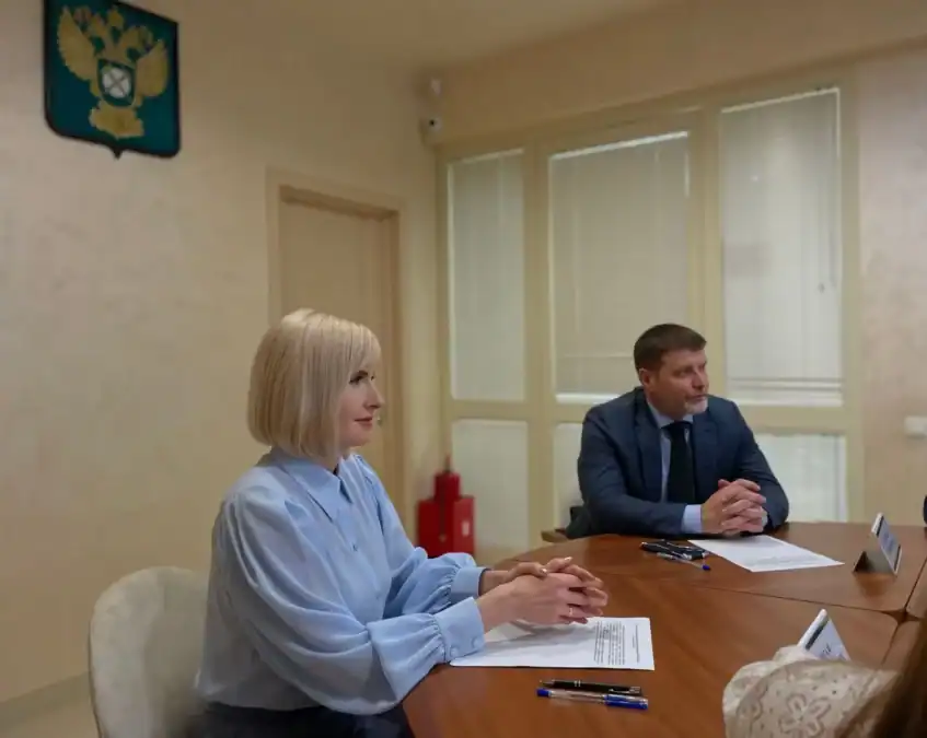 Мужчина и женщина сидят за столом с документами в кабинете.