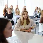 Студенты сидят за столами в светлом обновлённом пространстве.