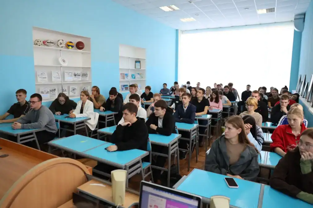 Студенты сидят за партами в аудитории во время лекции.
