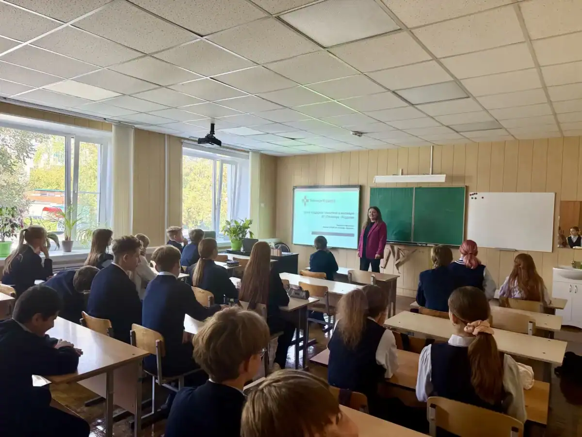 Преподаватель показывает презентацию ученикам, сидящим за партами в классе.