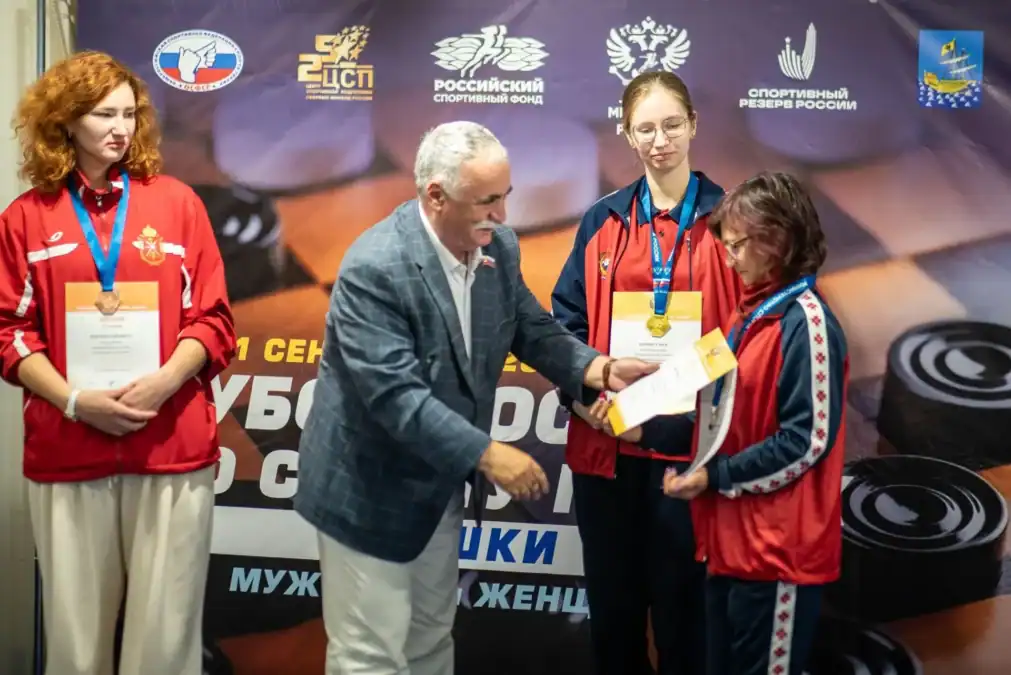 Мужчина вручает диплом спортсменке с медалью на шее.