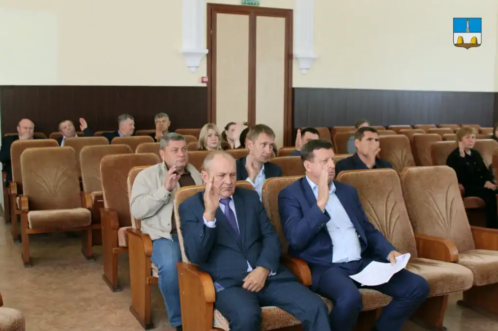 Участники заседания сидят в рядах кресел и слушают выступление.