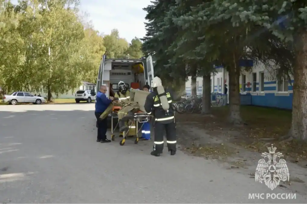 Спасатели в защитном снаряжении перевозят носилки к открытому служебному автомобилю.