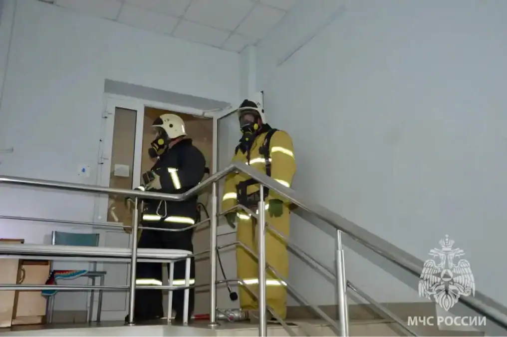 Два спасателя в дыхательных аппаратах находятся на лестничной площадке здания.