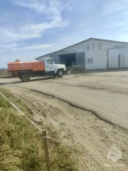 Пожарный автомобиль стоит у складского здания, территория огорожена лентой.