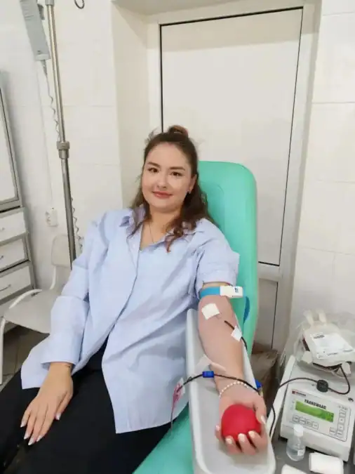 Девушка сдаёт кровь в донорском кресле, сжимая красный мяч.