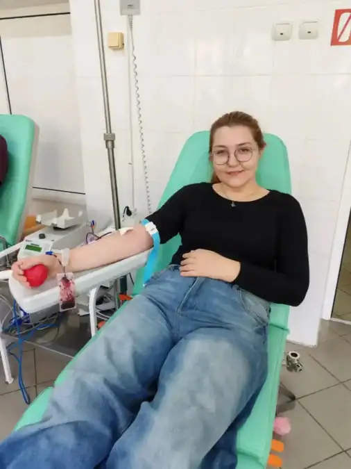 Девушка в очках сдаёт кровь в донорском кресле.