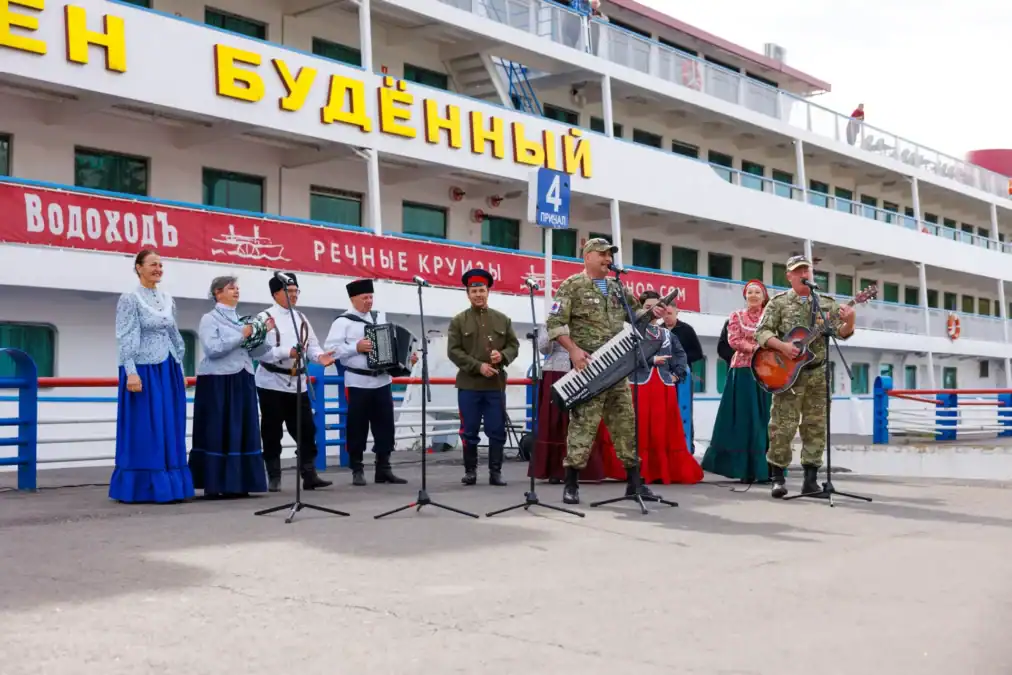 Музыканты и певицы в народных костюмах выступают у теплохода.