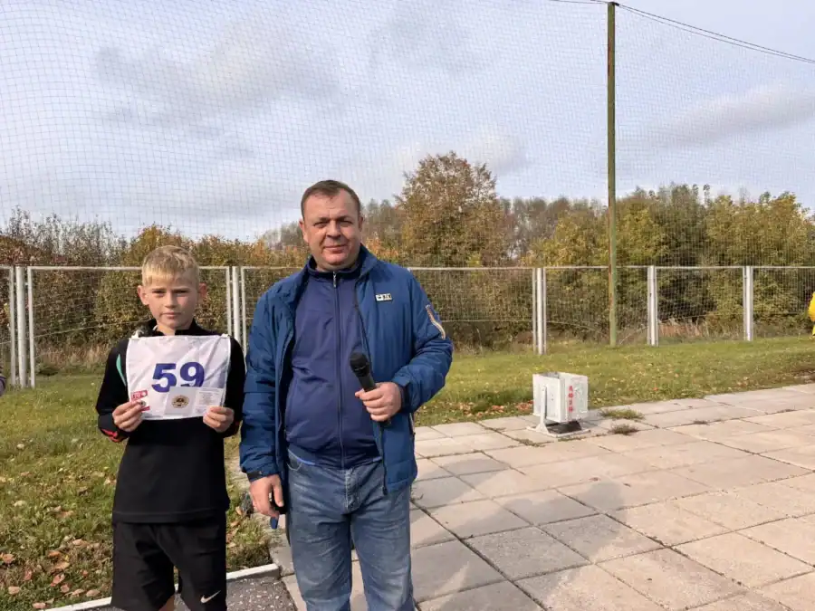 Мальчик держит карточку с номером 59 рядом с мужчиной с микрофоном.