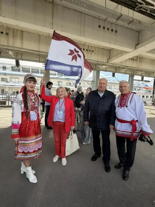 Участники в национальных костюмах стоят у причала с флагом Мордовии.