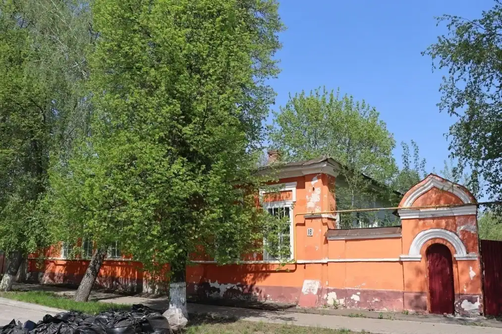Оранжевое старинное здание и арочные ворота с тёмно-красной дверью.