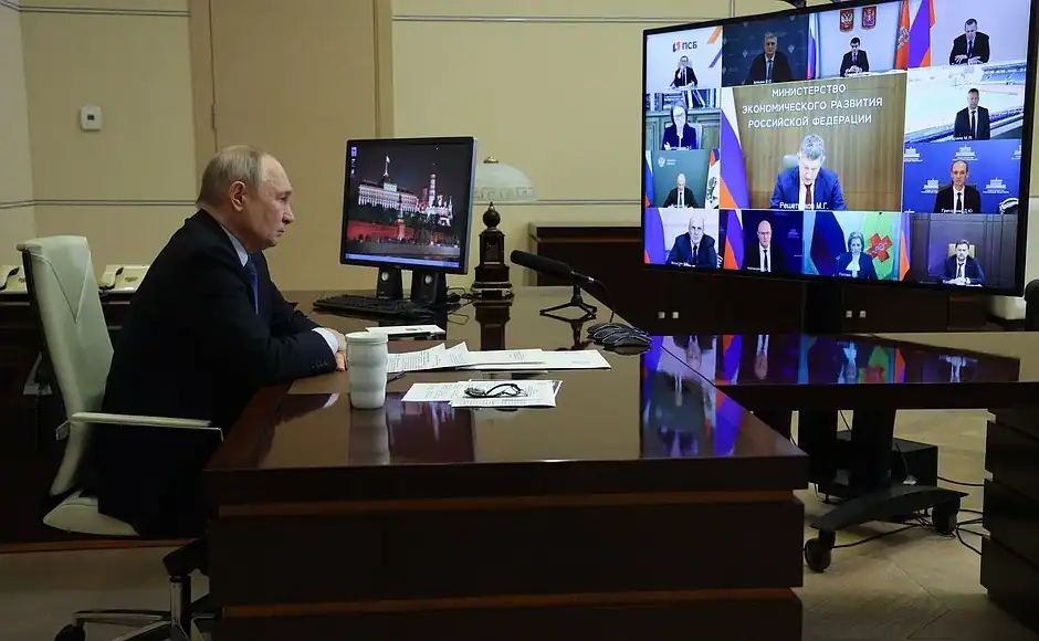 Президент за рабочим столом смотрит трансляцию совещания с членами правительства.