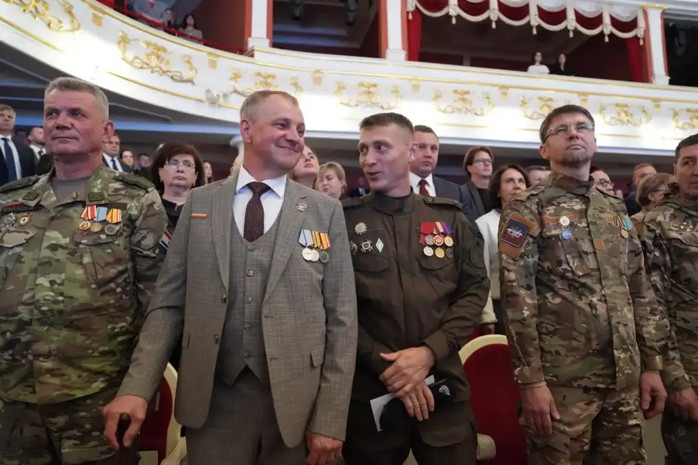 Мужчины в военной форме и с наградами стоят в зрительном зале.