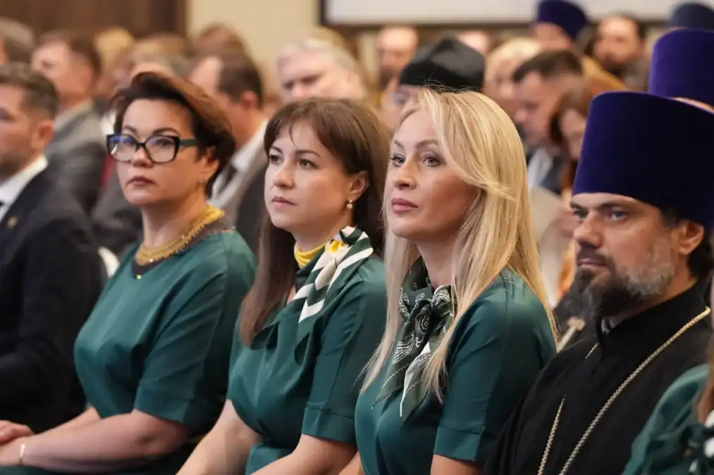 Участники форума сидят в зале рядом со священнослужителем.
