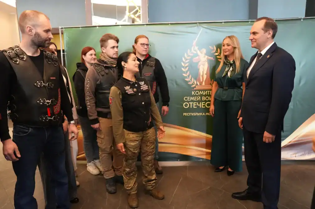 Группа людей стоит у баннера Комитета семей воинов Отечества.
