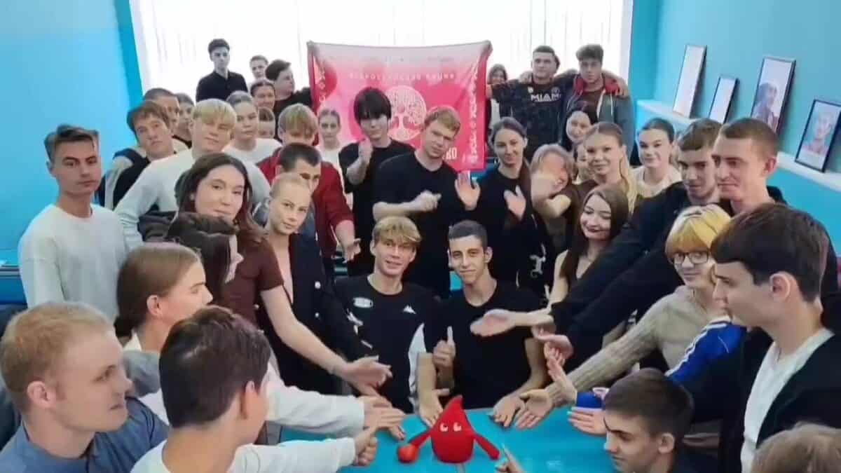 Студенты собрались вокруг стола с красной фигурой в форме капли.