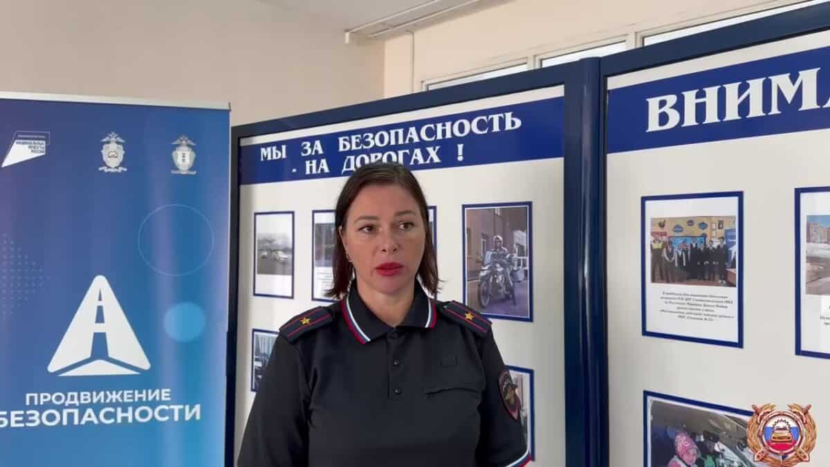 Сотрудница полиции стоит у стендов, посвящённых безопасности дорожного движения.