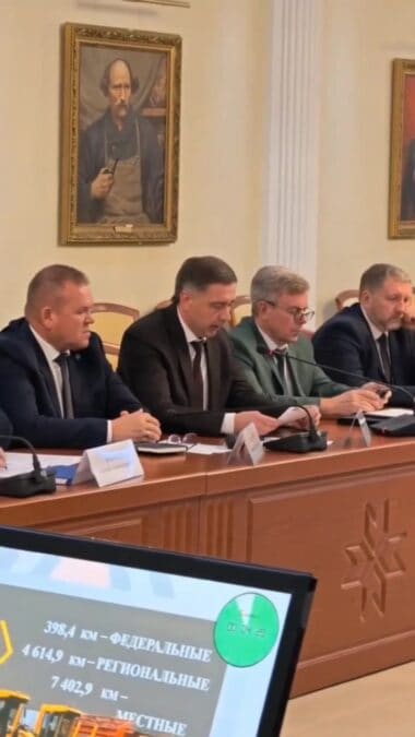 Четверо мужчин участвуют в заседании за длинным столом с микрофонами.