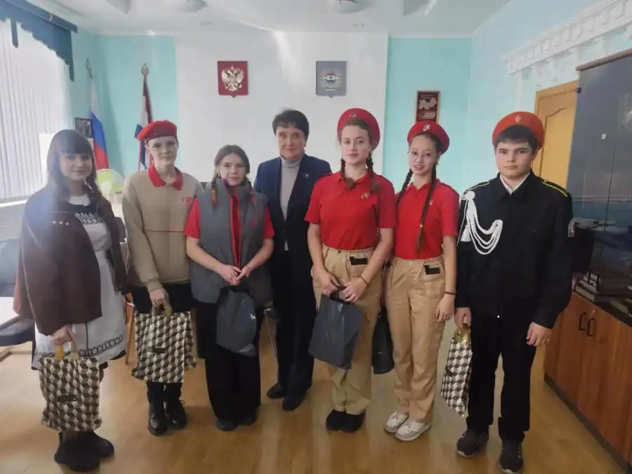 Семь участников совета и активистов позируют в кабинете с подарочными пакетами.