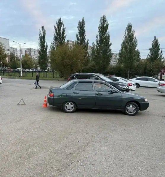 Зелёный ВАЗ стоит на парковке рядом с конусом и аварийным знаком.