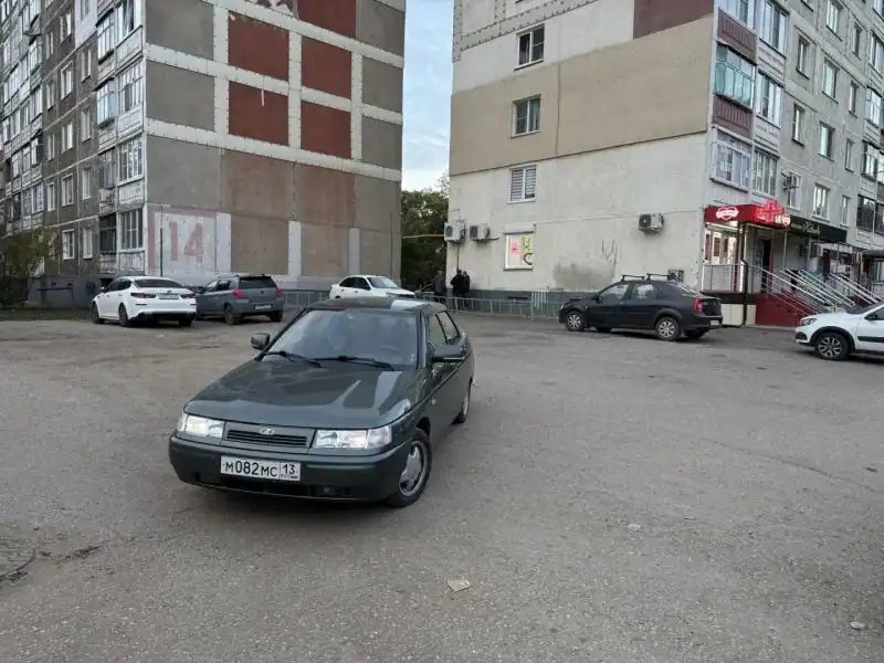 Зелёный ВАЗ стоит во дворе между многоэтажными домами.