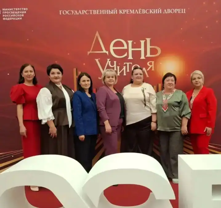 Семь женщин позируют перед стендом с надписью «День Учителя».