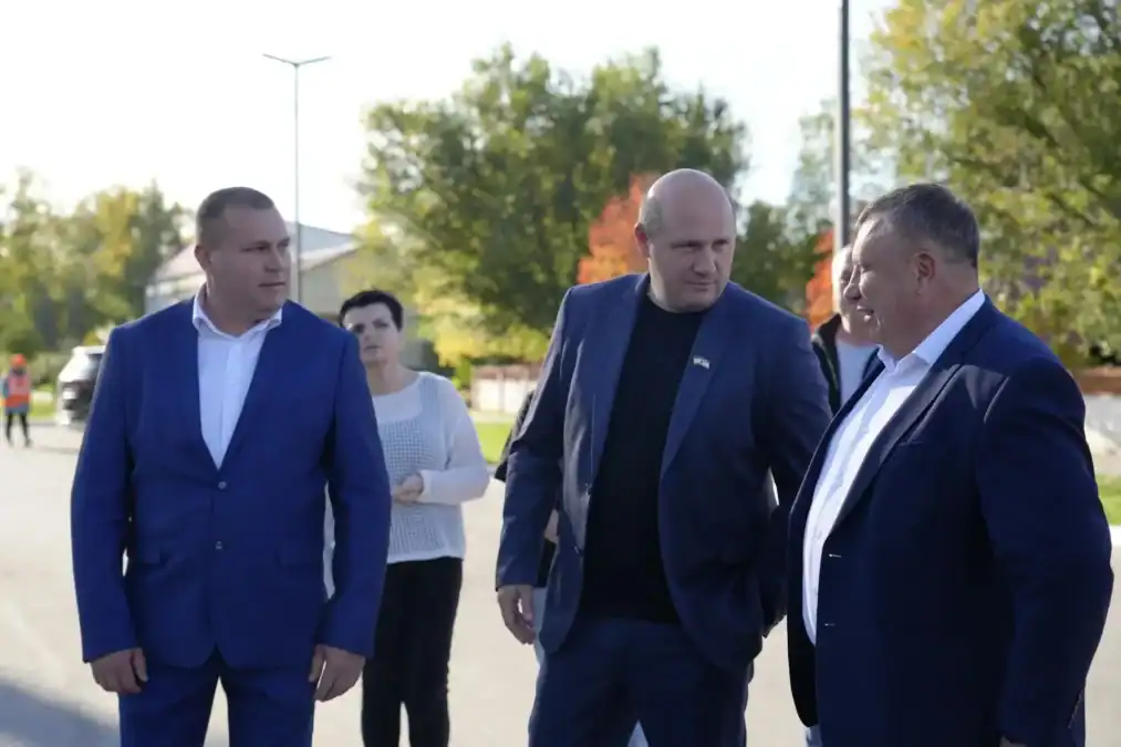 Трое мужчин в костюмах беседуют на городской площади.