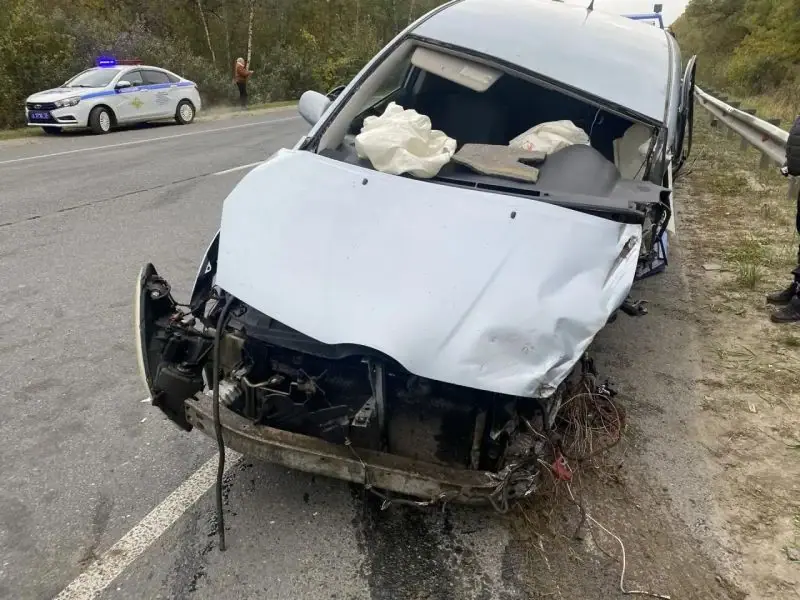 Автомобиль с сильно повреждённой передней частью стоит на обочине, вдали виден патрульный автомобиль.