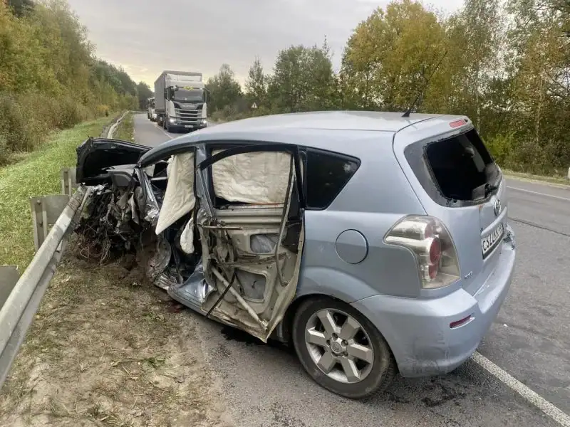 Серебристый автомобиль с разрушенной передней частью стоит у дорожного отбойника.