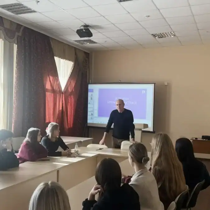 Мужчина проводит занятие для школьников в аудитории у проекционного экрана.