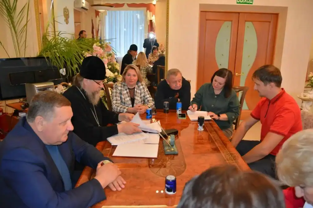 Участники деловой встречи обсуждают документы за длинным столом.