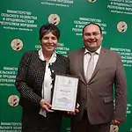 Женщина держит диплом рядом с мужчиной у стенда Минсельхозпрода Мордовии.