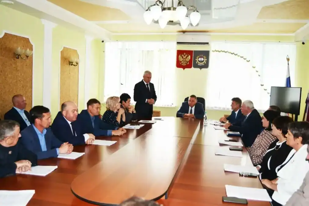 Мужчина выступает перед участниками заседания за длинным столом.