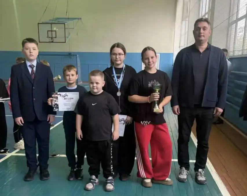 Дети и подростки с дипломами, медалью и кубком стоят в зале.