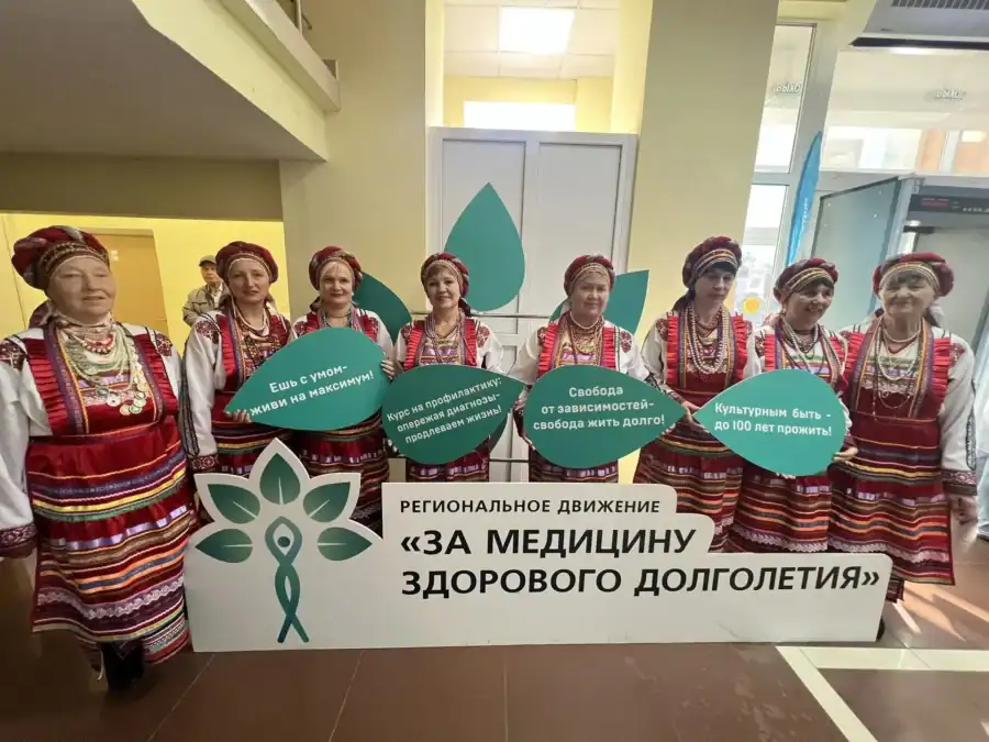 Участницы в народных костюмах стоят с табличками движения здорового долголетия.