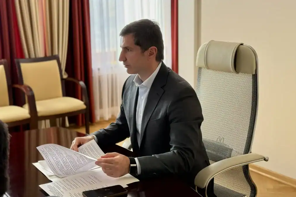Мужчина в кабинете просматривает документы за столом.