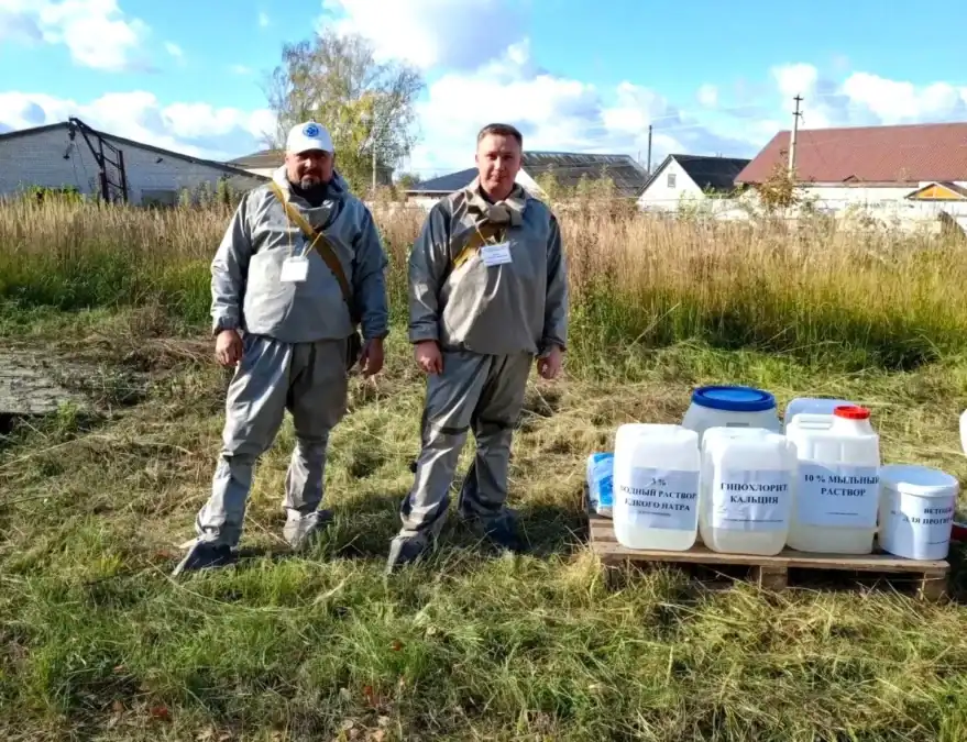 Два специалиста стоят рядом с ёмкостями для дезинфицирующих средств.