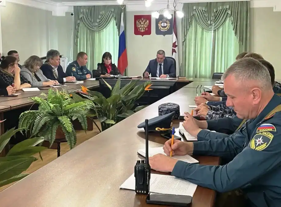 Участники заседания гражданской обороны сидят за длинным столом в администрации.