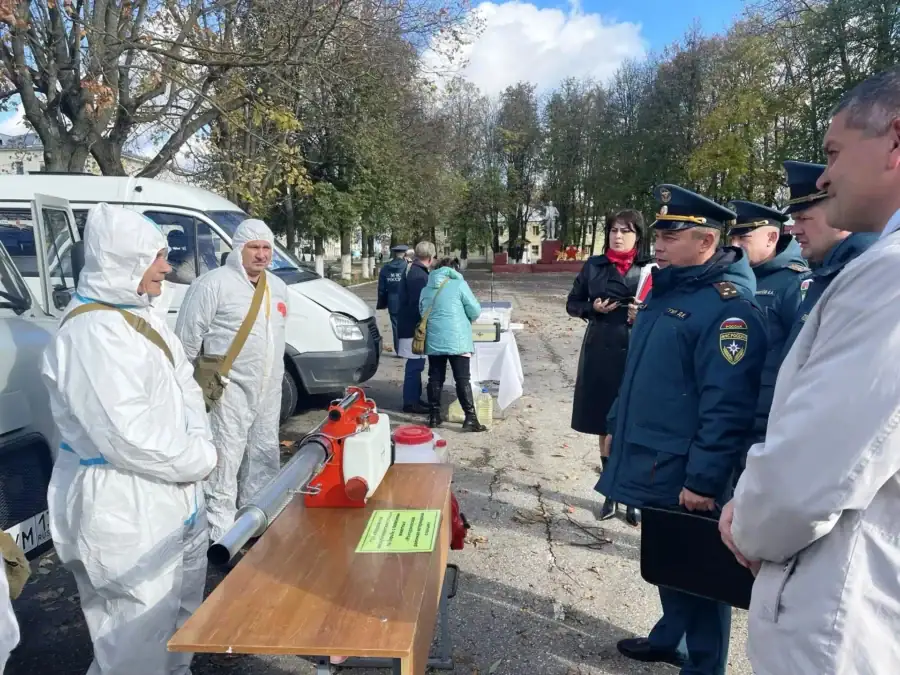 Сотрудники в защитных костюмах показывают оборудование представителям экстренных служб.