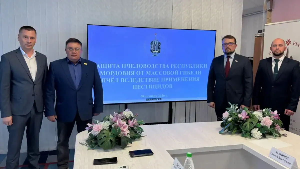 Четверо мужчин стоят у экрана с темой защиты пчеловодства от пестицидов.