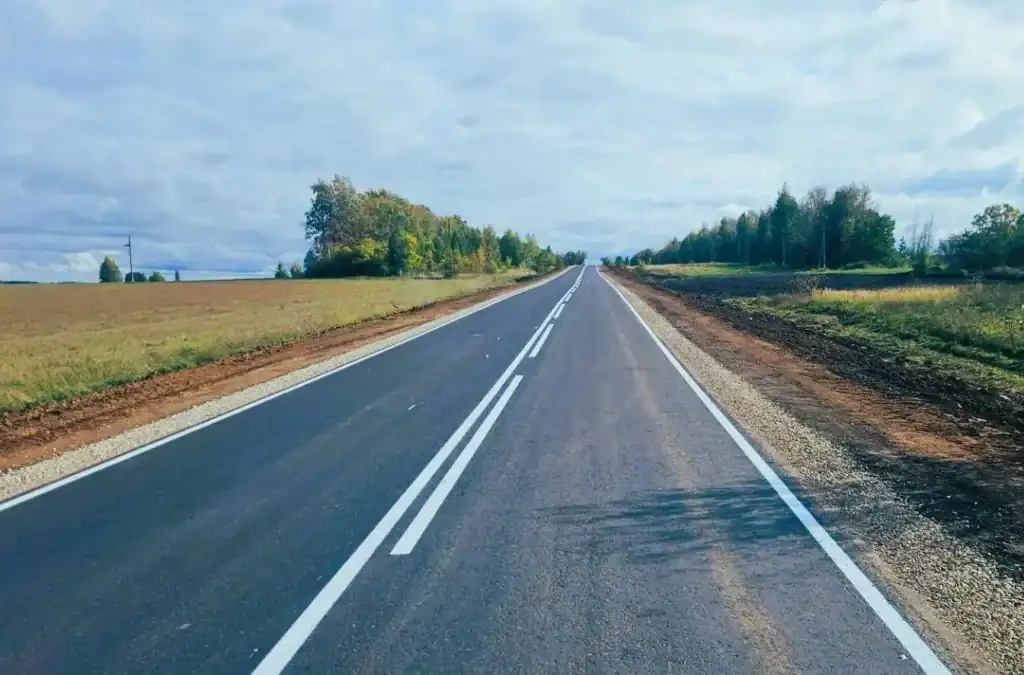 Обновлённая асфальтированная дорога с двойной сплошной разметкой среди полей.