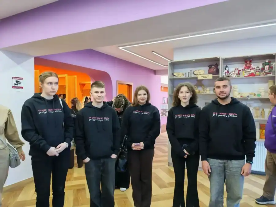 Пятеро молодых людей в чёрных худи стоят в музейном помещении.