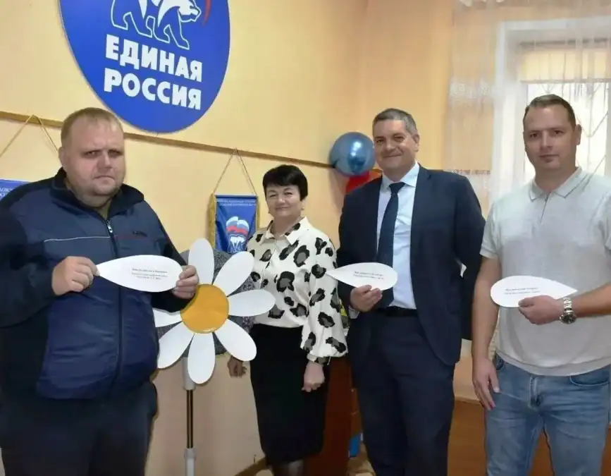 Четверо участников акции стоят у бумажной ромашки и держат лепестки.