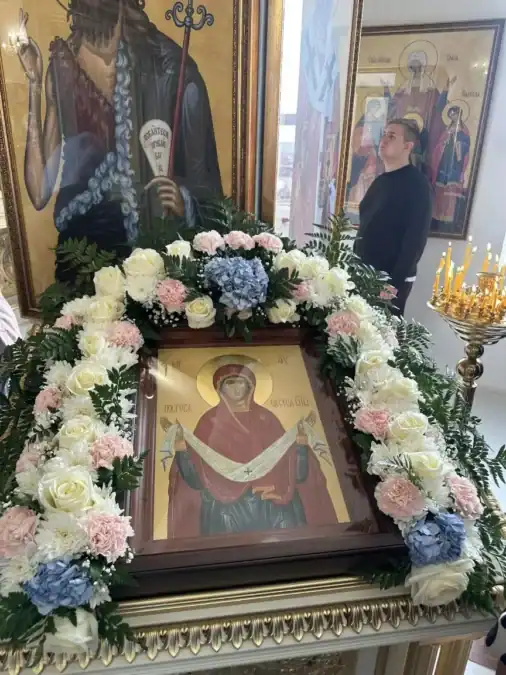 Украшенная цветами икона стоит рядом с подсвечником в храме.
