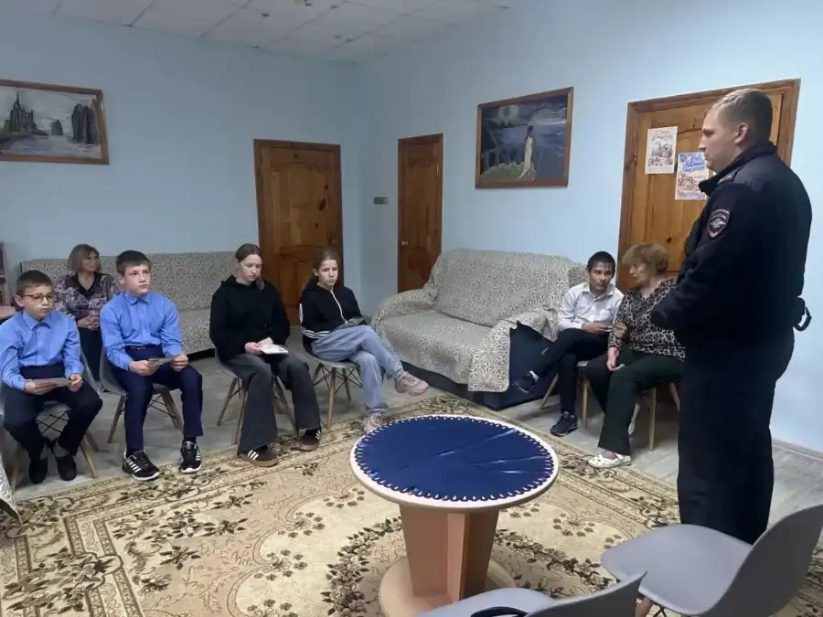 Сотрудник полиции выступает перед подростками в небольшой комнате.